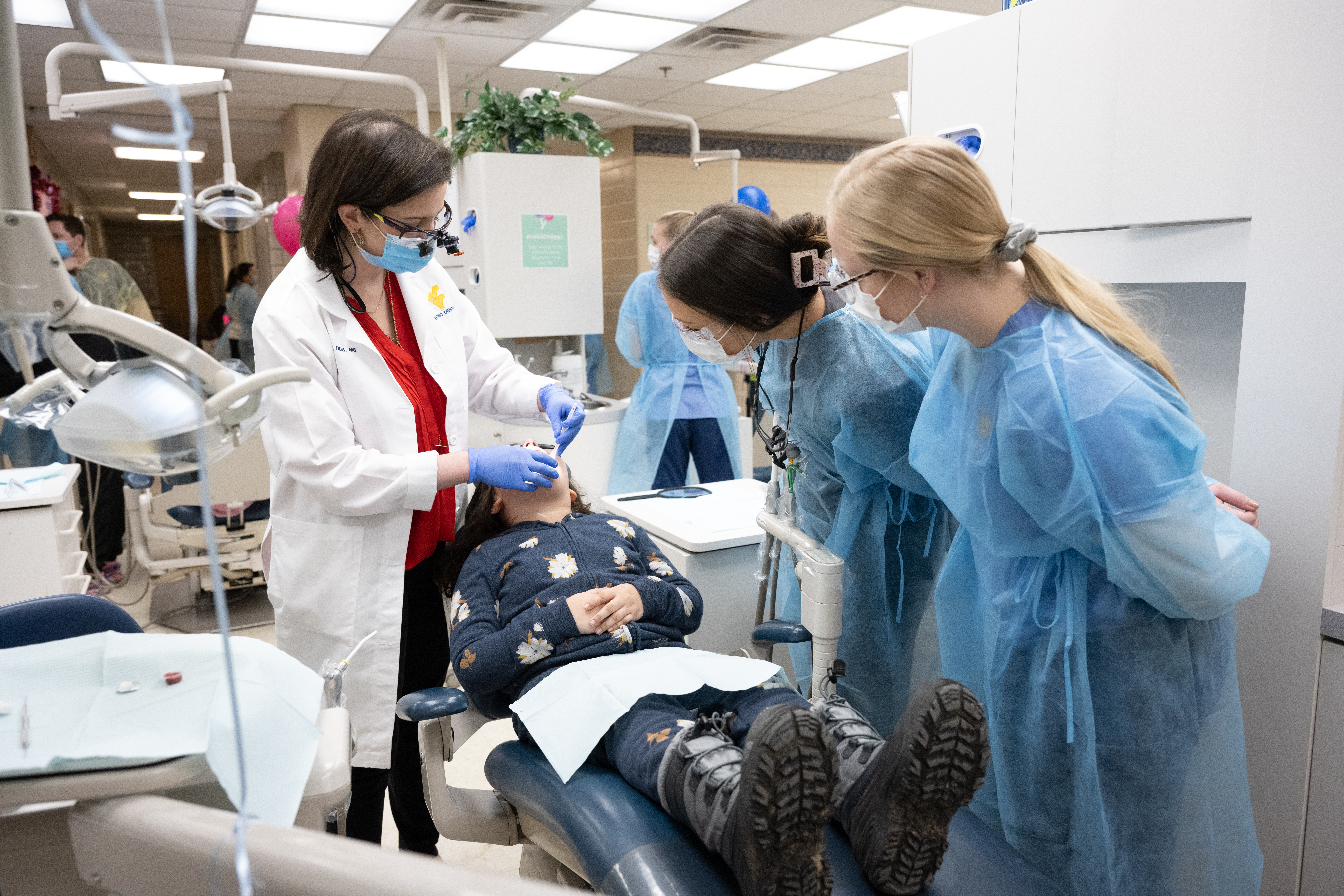 Faculty and students work with a child in the pediatric dentistry clinic. 